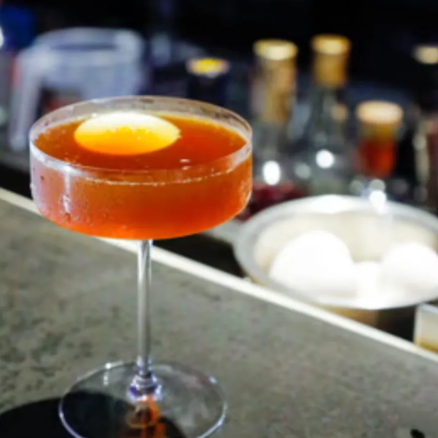 Amber cocktail in a coupe glass on the bar.