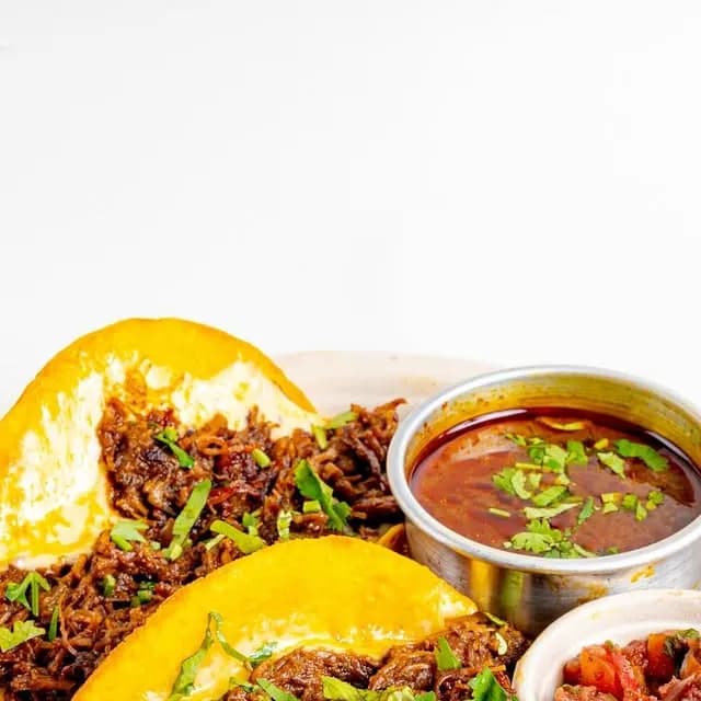 Beef tacos with melted cheese, chopped herbs, salsa and a bowl of consomme