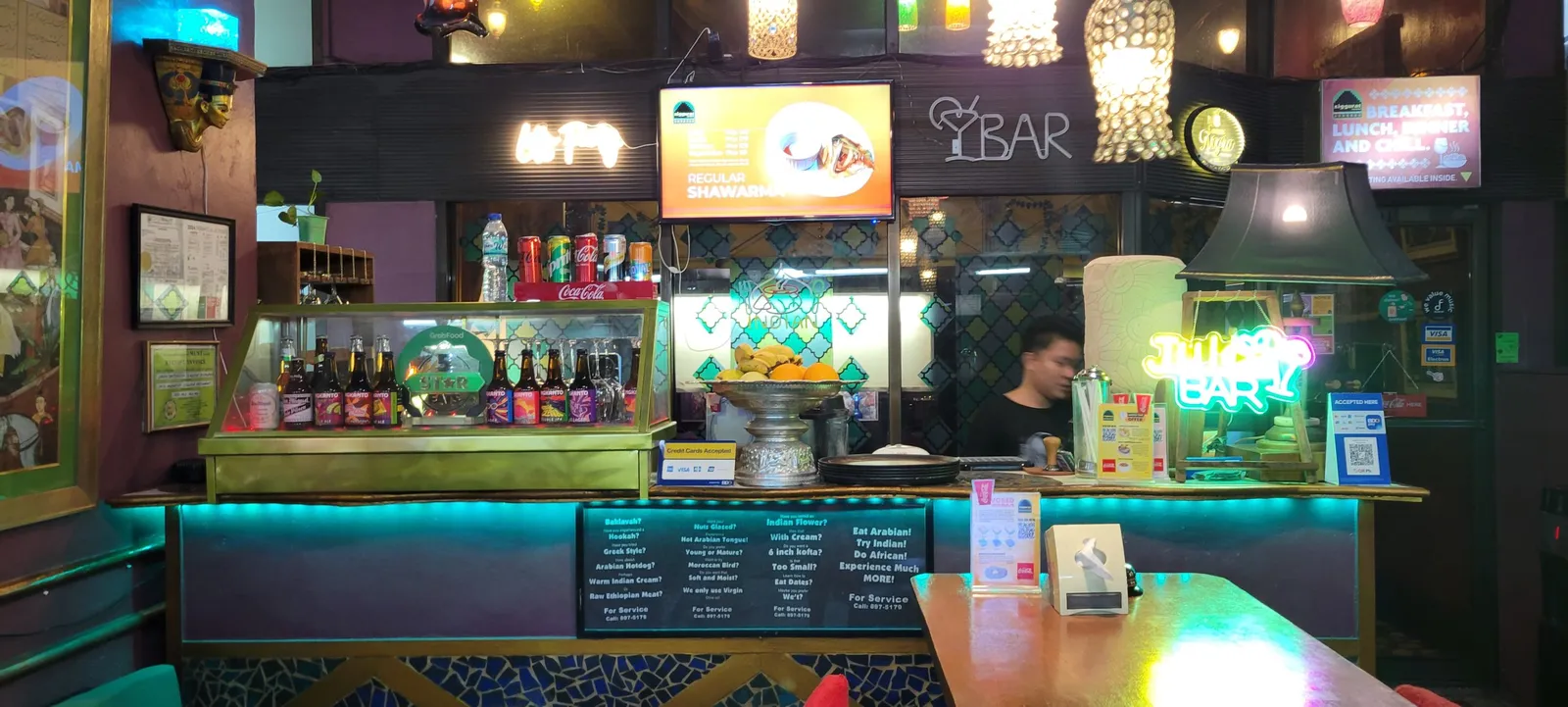 Illuminated bar counter with bottled drinks, fruit and hanging lamps