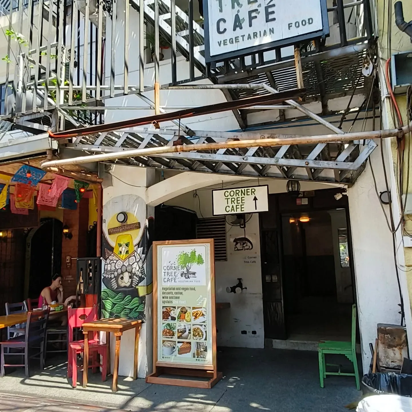 Street-level entrance to Corner Tree Cafe with signs pointing upstairs