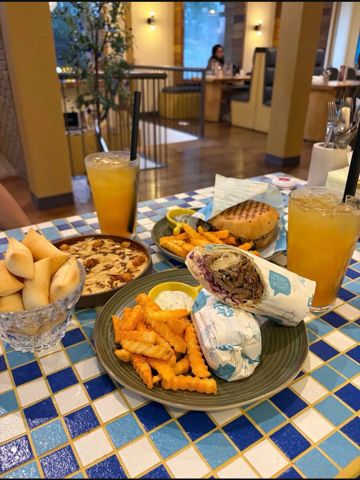 Shawarma wraps, fries, dips and iced drinks spread across a tiled table