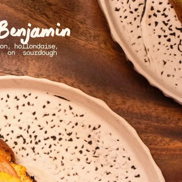 Eggs Benjamin served on patterned plates on a wooden table.