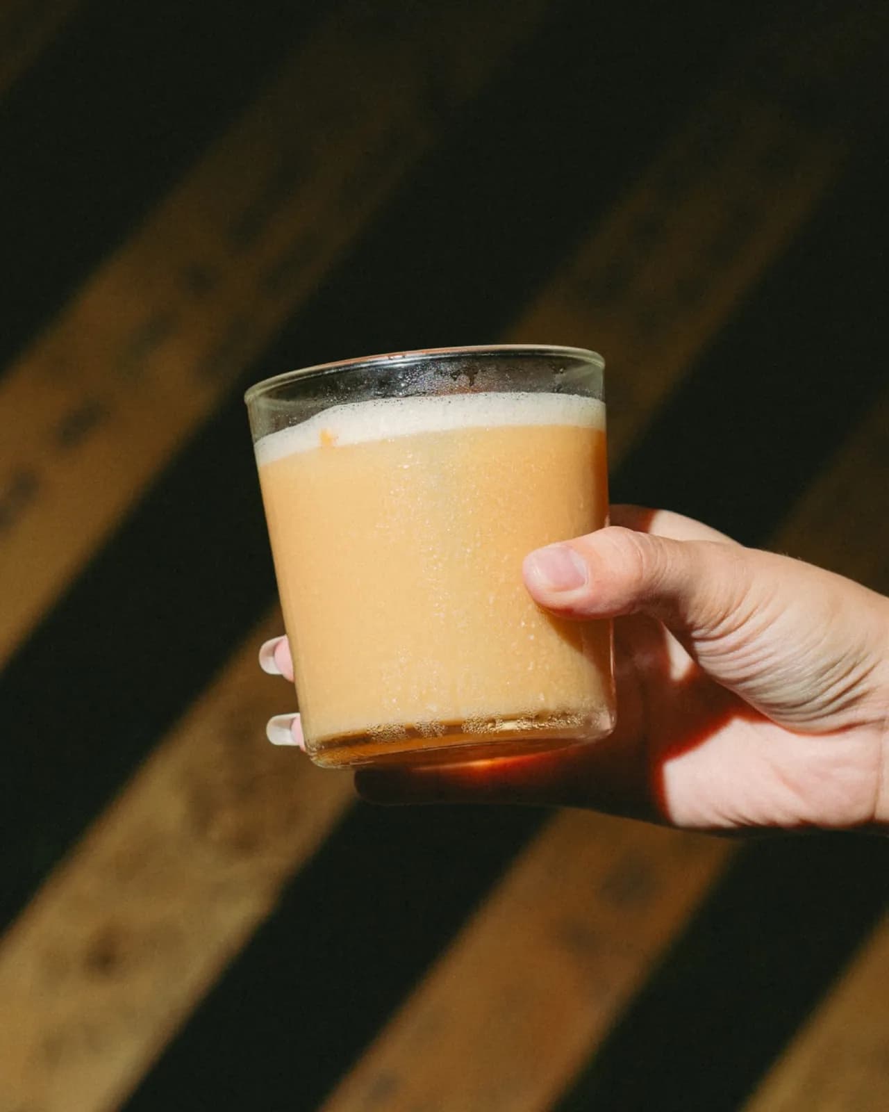 Cold coffee drink in a short glass against OTO's striped wall