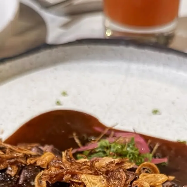 Beef dish with fried garlic, herbs and red sauce
