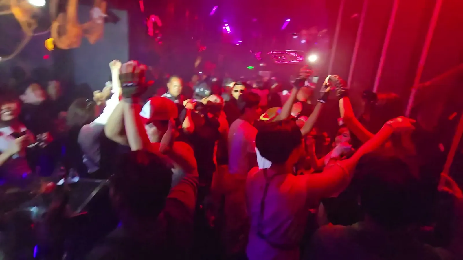 Late-night crowd dancing under red and purple lights