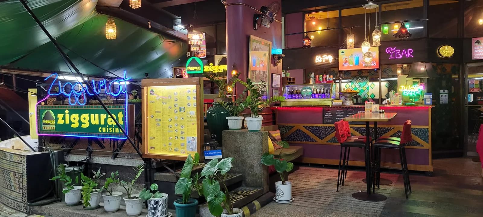 Restaurant entrance and bar lit with colorful neon signs and pendant lamps