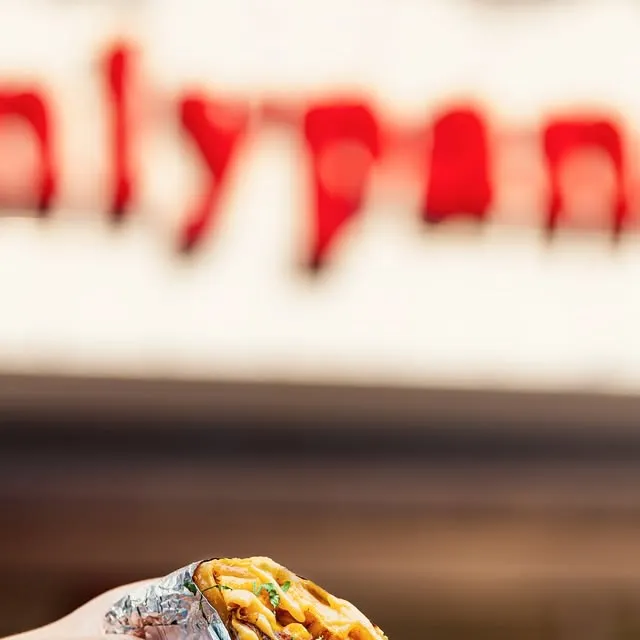 Foil-wrapped burrito held in front of the red Onlypans sign