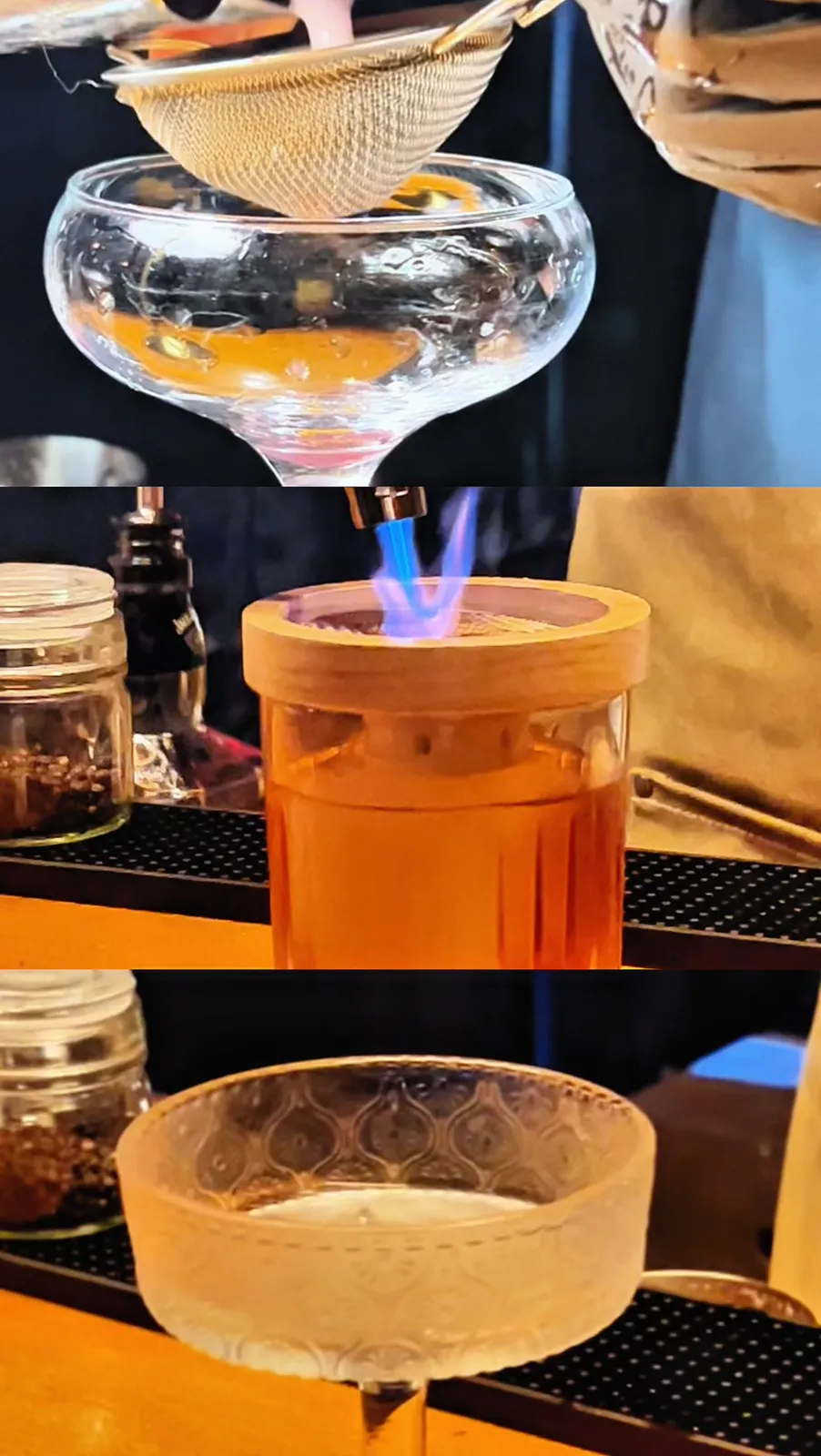 A cocktail being strained, flamed and served behind the bar.