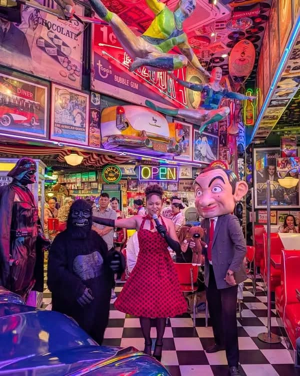 Costumed entertainers performing inside the neon-lit retro dining room.