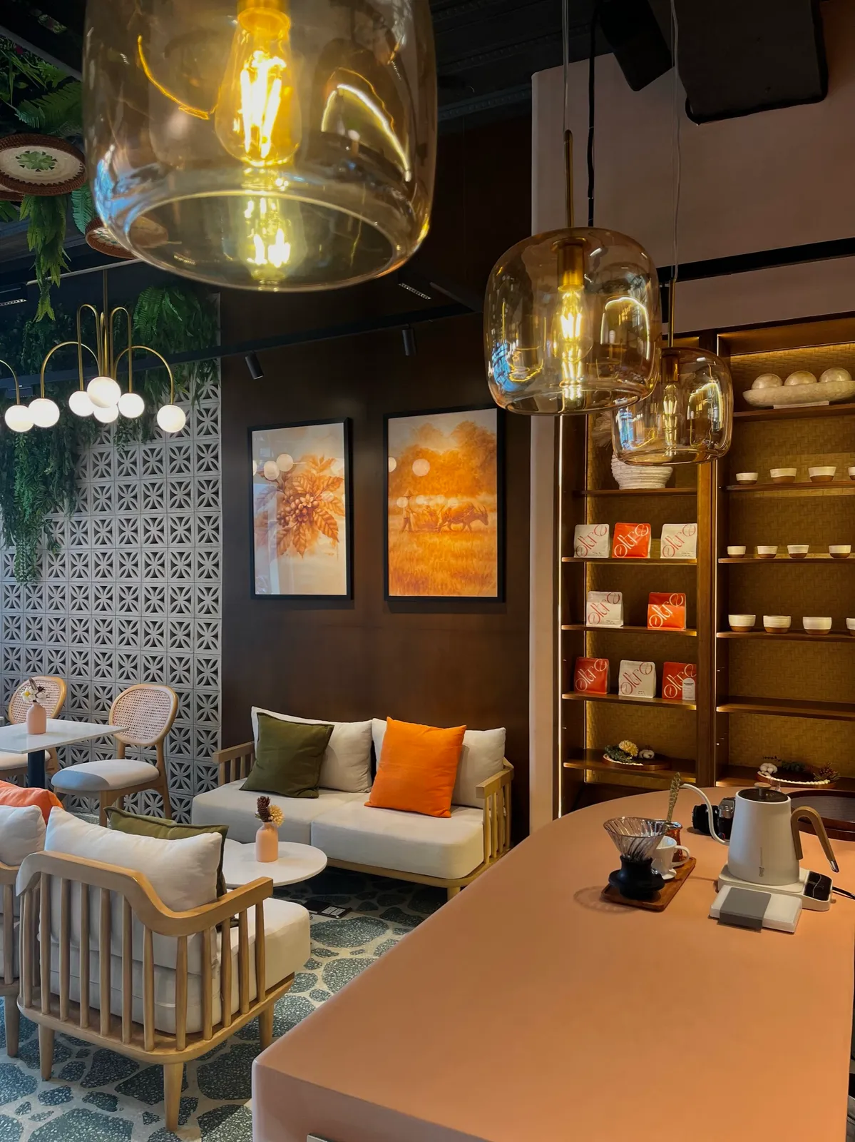 Warm café lounge with cushioned chairs, pendant lights and a pour-over counter
