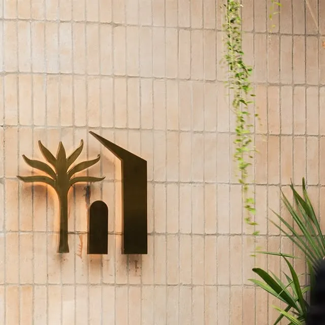 Treehouse wall sign beside trailing and potted plants.