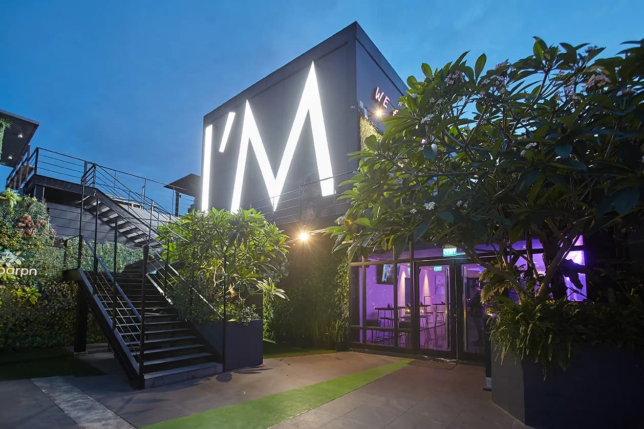 Planted rooftop entrance and illuminated hotel sign at dusk.