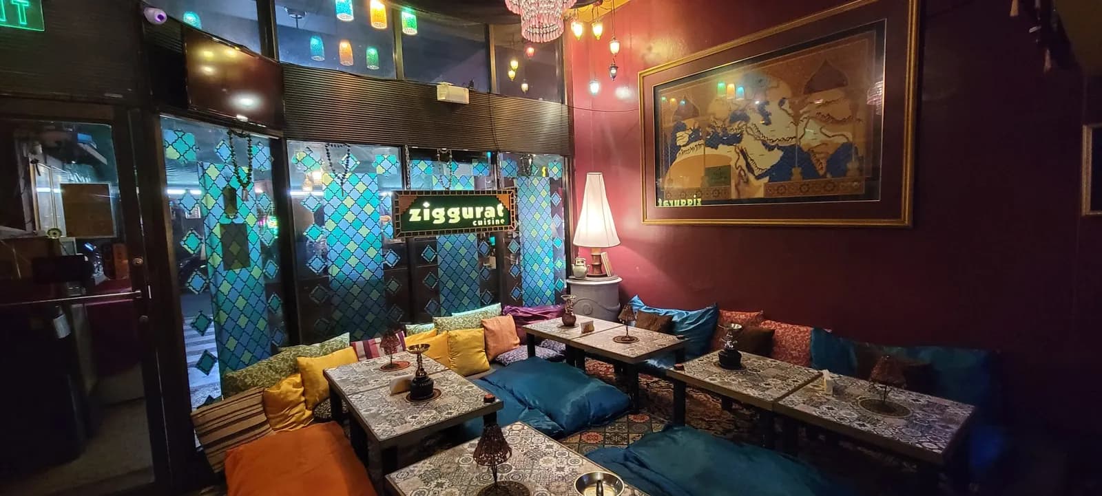 Colorful low-table seating with cushions, patterned windows and hanging lamps