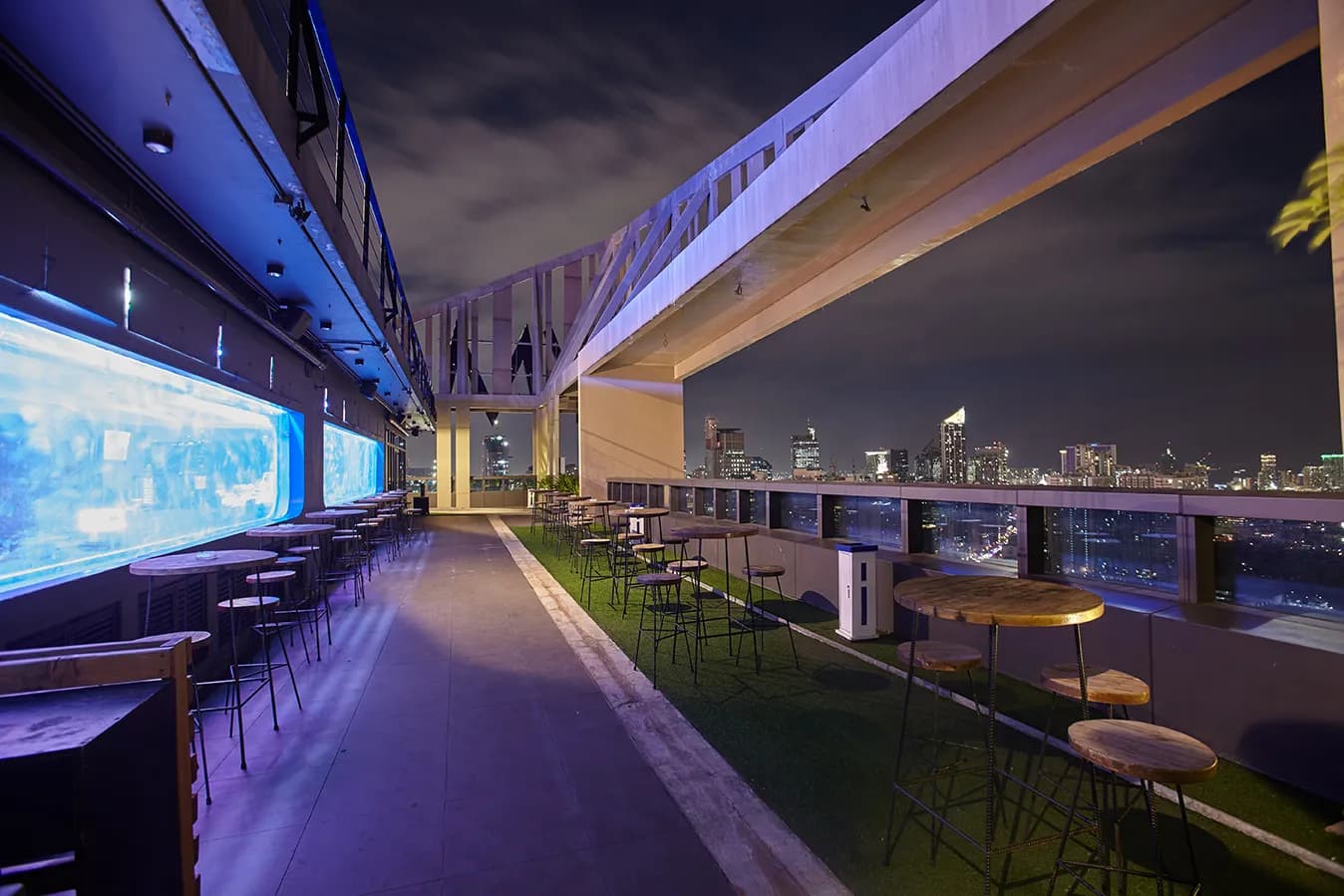 Open-air terrace beside the glowing jellyfish tank with the skyline beyond.