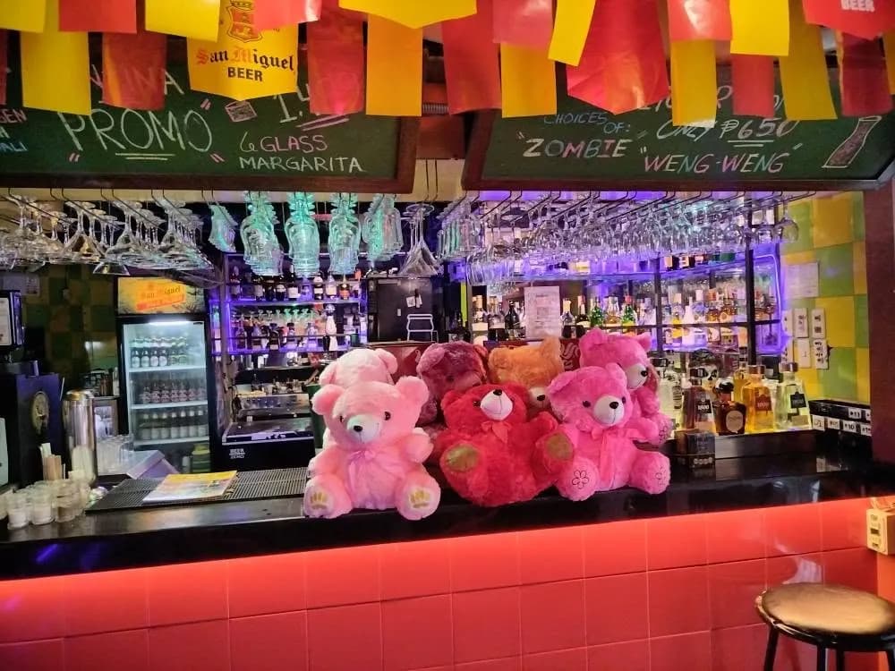 Cantina bar counter with backlit bottles, red stools and colorful decorations